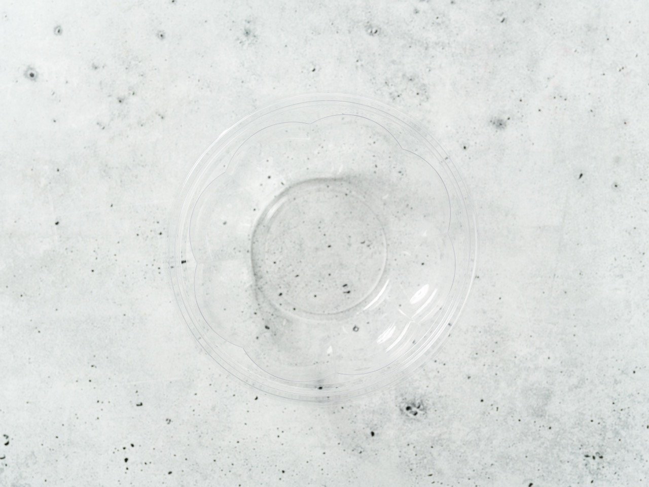  An empty clear glass bowl on a speckled grey surface 