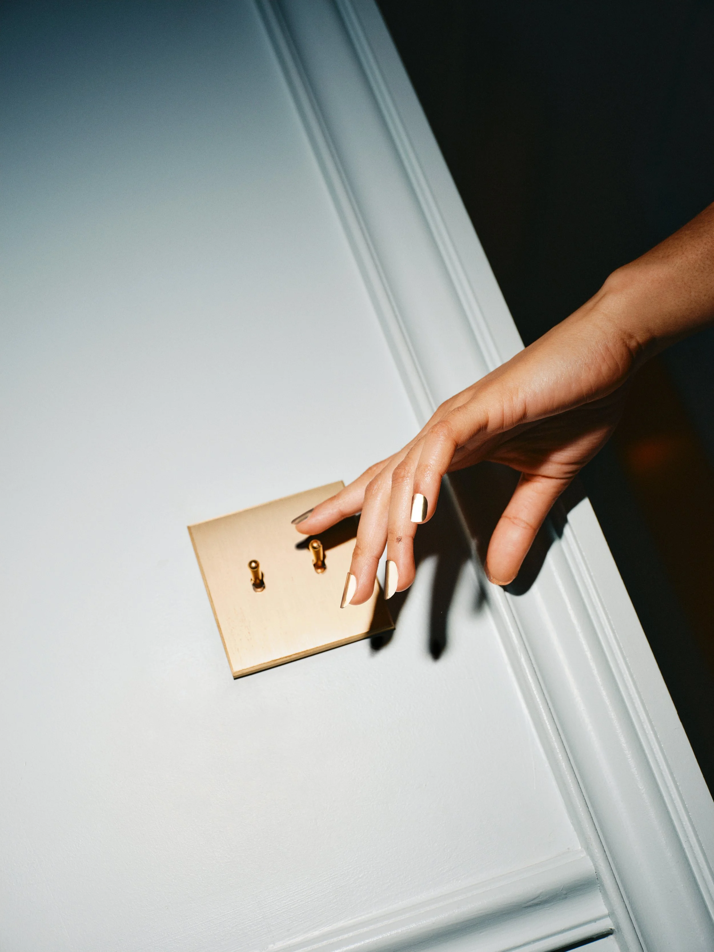 Model reaching for light switch wearing 14k white gold press-on nails by Stey Gold with mirror finish