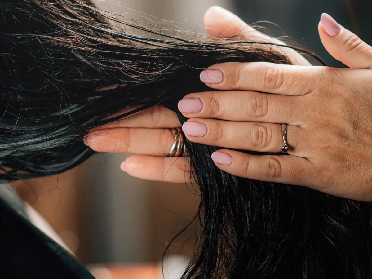 Close-up of a woman's hands gently running through another person's dark hair, evoking the quiet ritual of hair passed down through generations