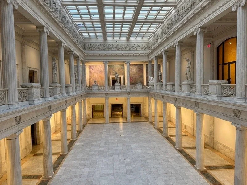Interior of the Carnegie Museum of Art Pittsburgh, featuring the hall of Sculpture with classical statues, marble columns, and a skylit gallery space.