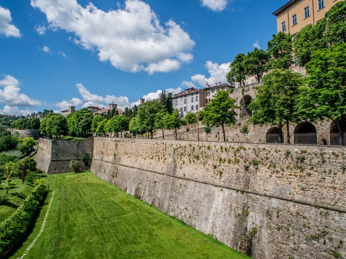 Ancient Venetian Walls surrounding Bergamo's Città Alta with tree-lined pathways and views across Lombardy, Italy.