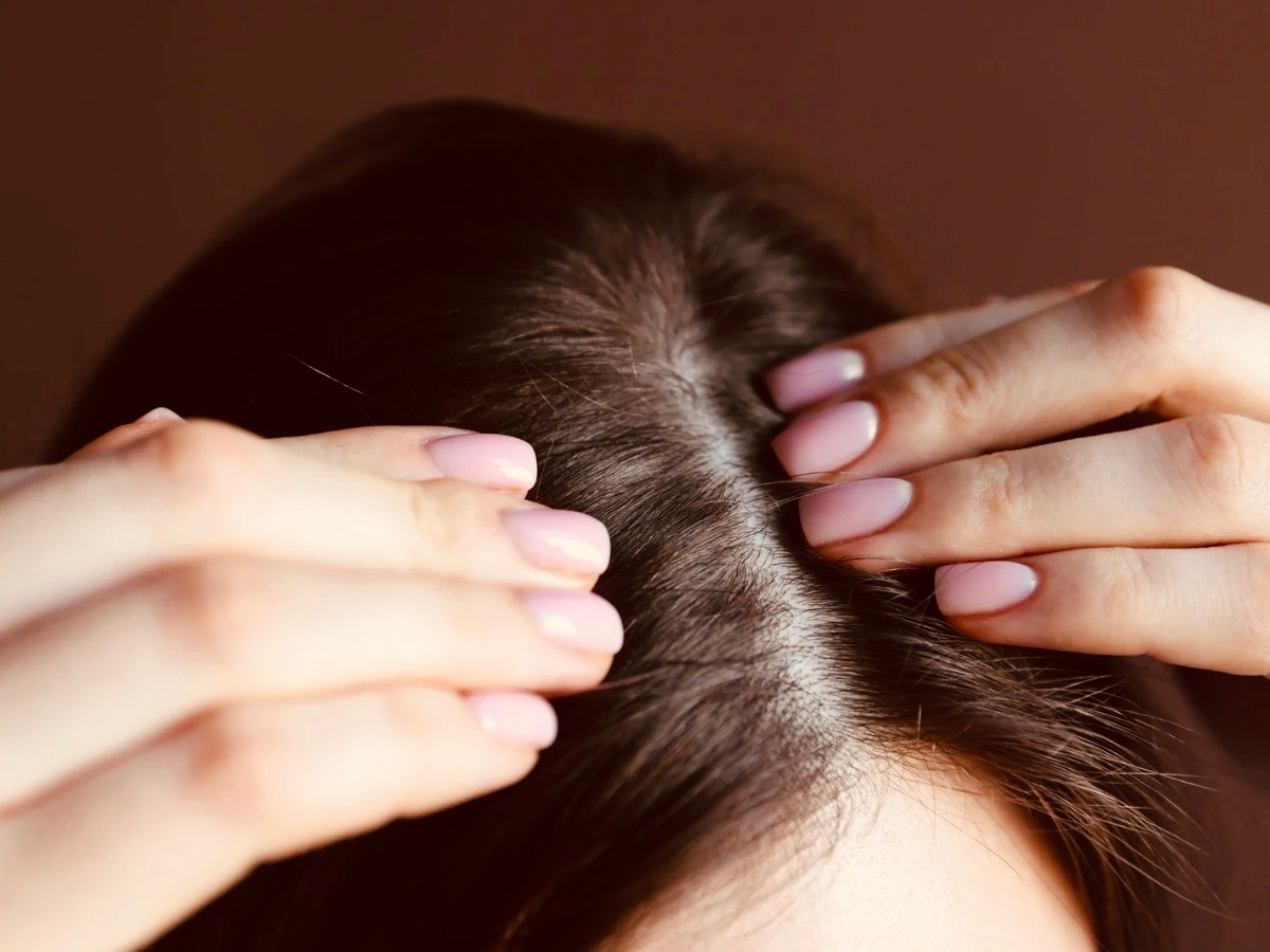 Close-up of hands massaging the scalp with fingertips — illustrating the application technique for a natural apple cider vinegar and peppermint scalp treatment.