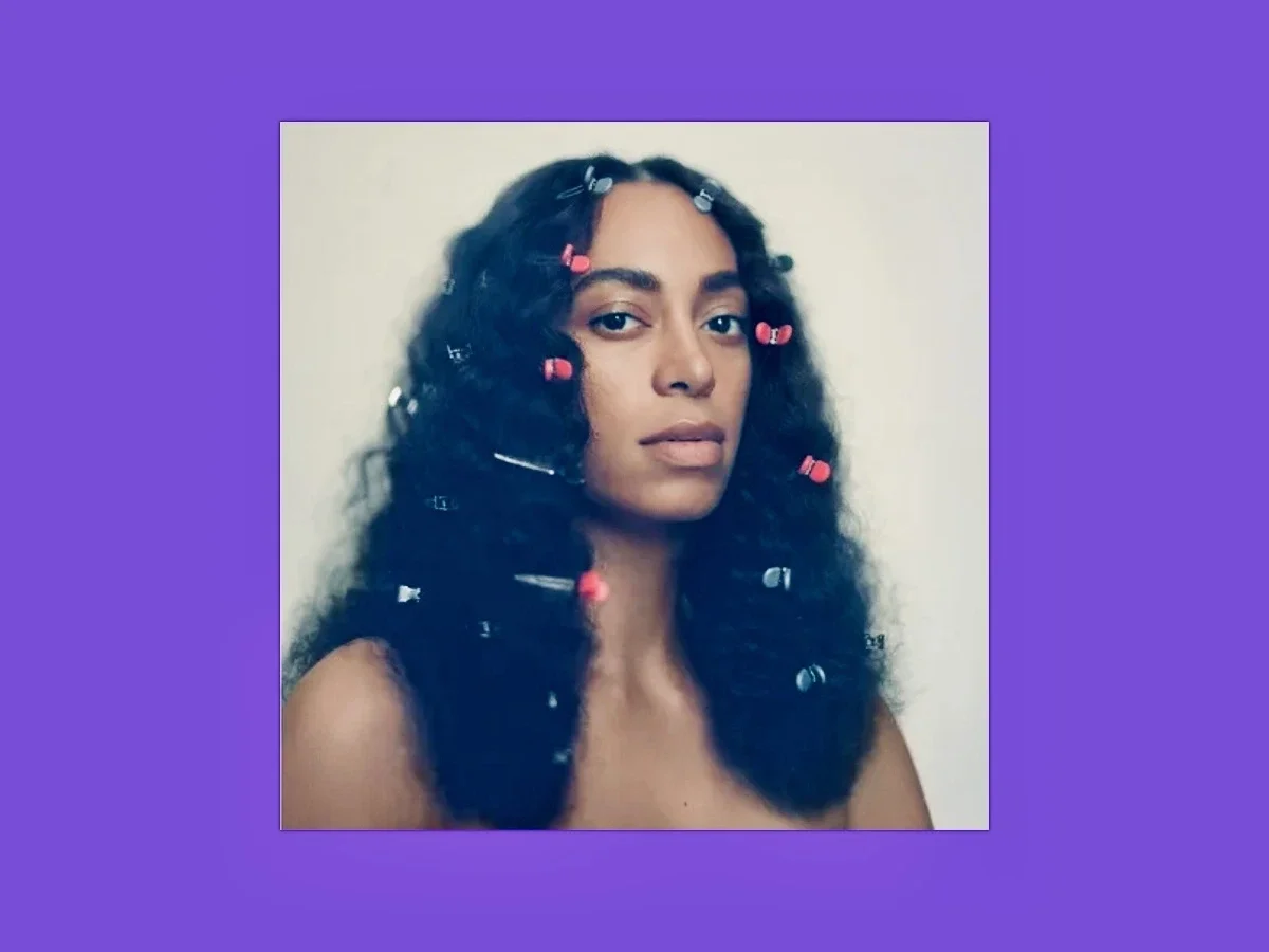 Album cover for Solange’s “A Seat at the Table,” featuring a purple background and minimalist portrait composition evoking themes of calm, identity, and emotional reflection.