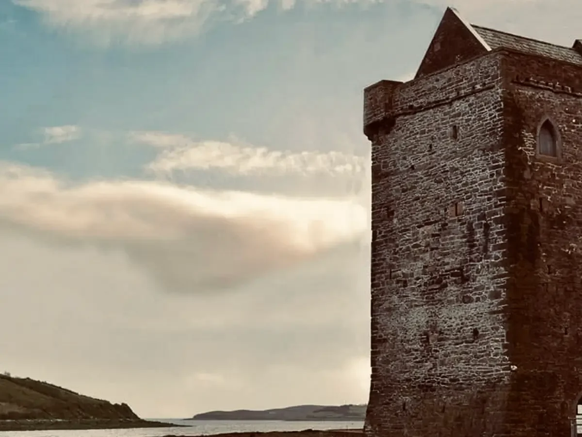 A weathered stone tower standing beside a coastal inlet, evoking the fortified landscape of Ireland in The Pirate Queen.