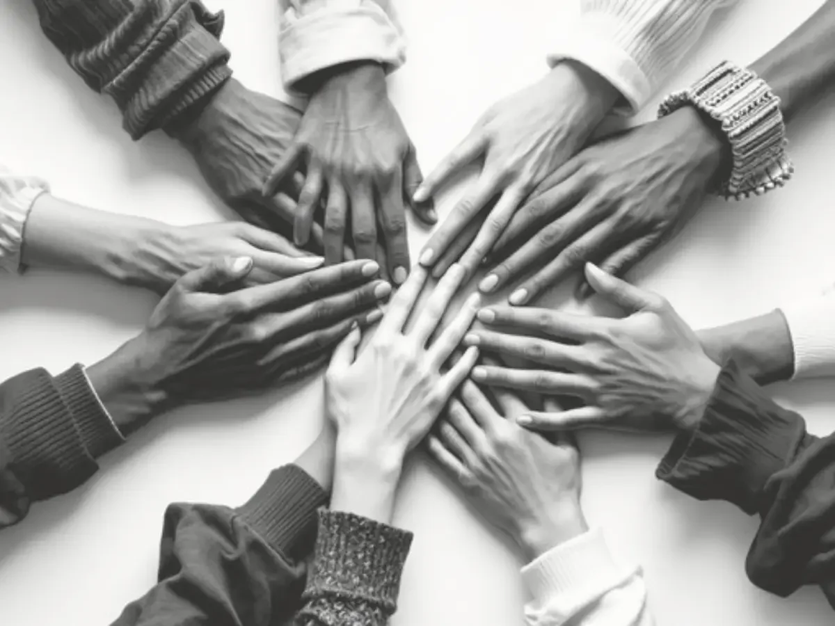 A circle of hands of varying ages and skin tones, stacked together at a central point, in black and white — accompanying "What Five Strangers Built Instead," the section of She The King's essay "The Water Family" on chosen family over blood.
