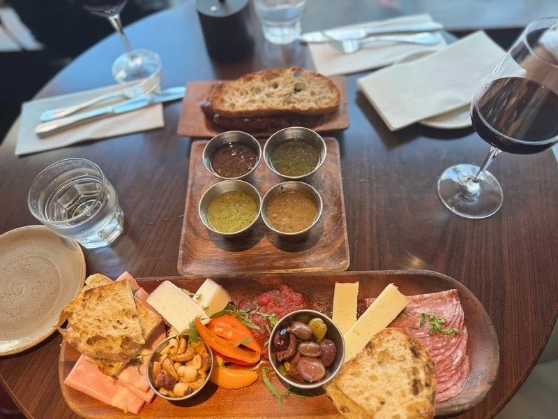 Artisan charcuterie board with cured meats, cheeses, olives, bread, and wine at a Pittsburgh restaurant, highlighting the city’s refined and globally influenced food scene during a cultural weekend visit.