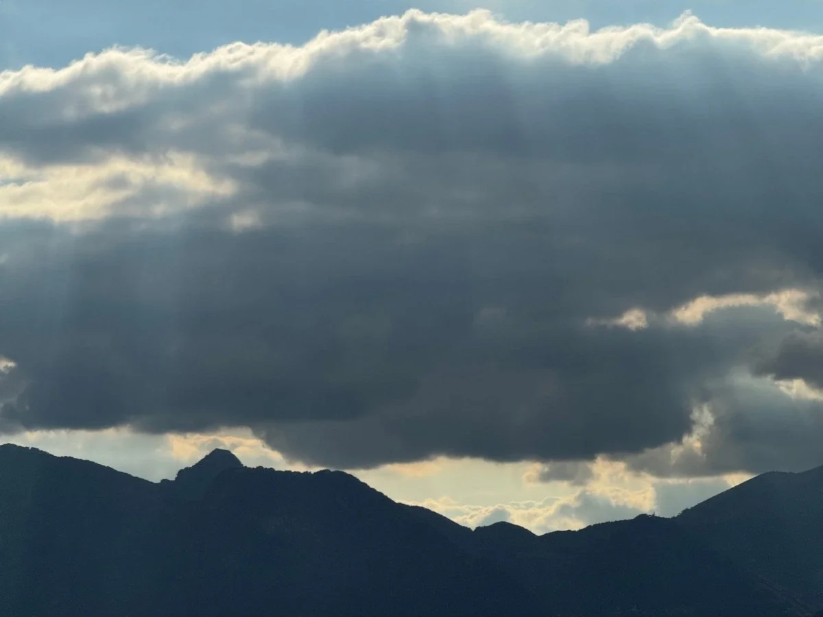 Dark storm clouds break over mountain silhouettes and open water, capturing the sense of scale and awe central to Turner's and Friedrich's Romantic landscapes.