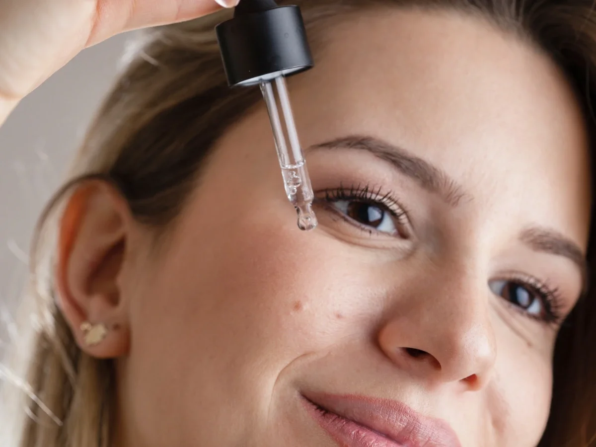 Close-up of woman applying a hydrating face serum with a dropper as part of an in-flight skincare routine
