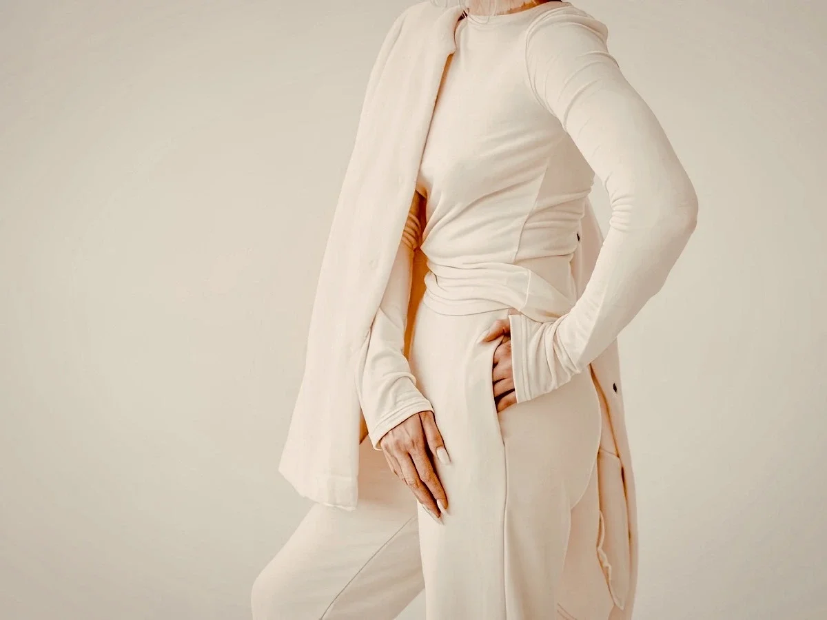 Woman in tonal cream long-sleeve top and wide-leg trousers with an open cardigan, illustrating the concept of investing in timeless, high-quality wardrobe staples