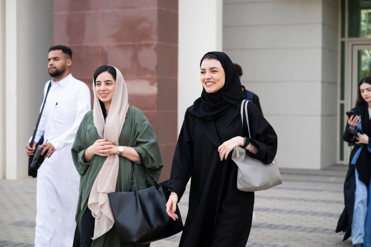 Professional women walking confidently outside a modern building, representing female authority across cultures and the intersection of femininity, leadership, and travel.