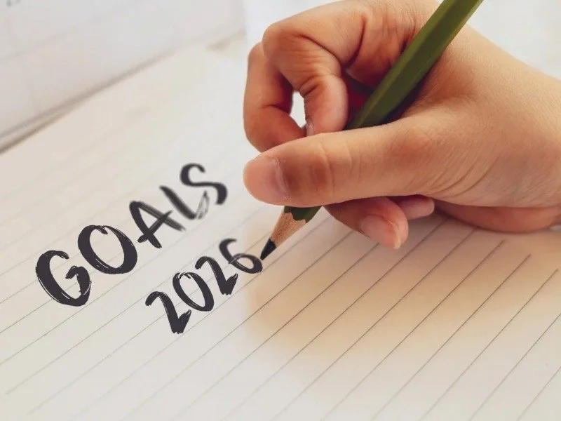 Hand writing ‘Goals 2026’ in a notebook, representing micro-habits, intentional goal-setting, and a gentle reset for the new year.