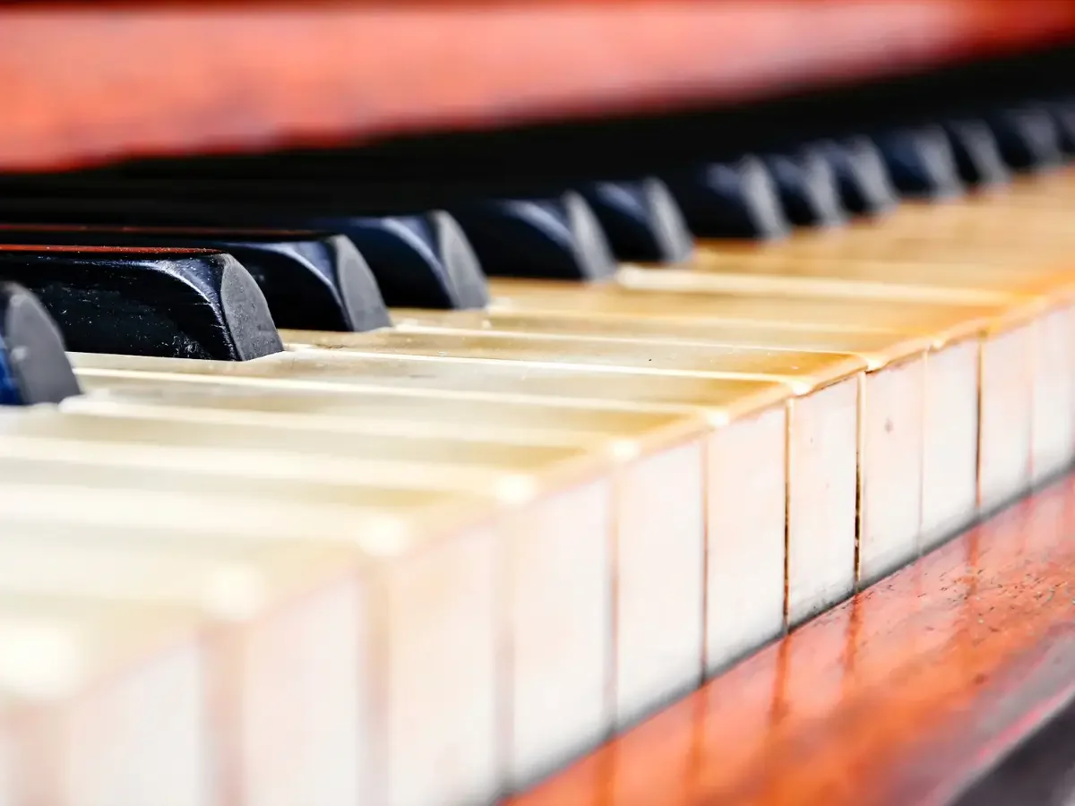 Close view of piano keys in warm light, a few worn smooth from years of playing.