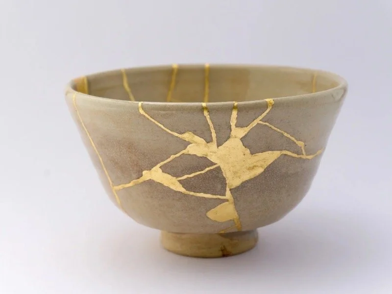 A beige ceramic bowl repaired with gold kintsugi lines, representing Japanese craftsmanship and mindful art—an ideal calming, museum-inspired gift for serene home decor.