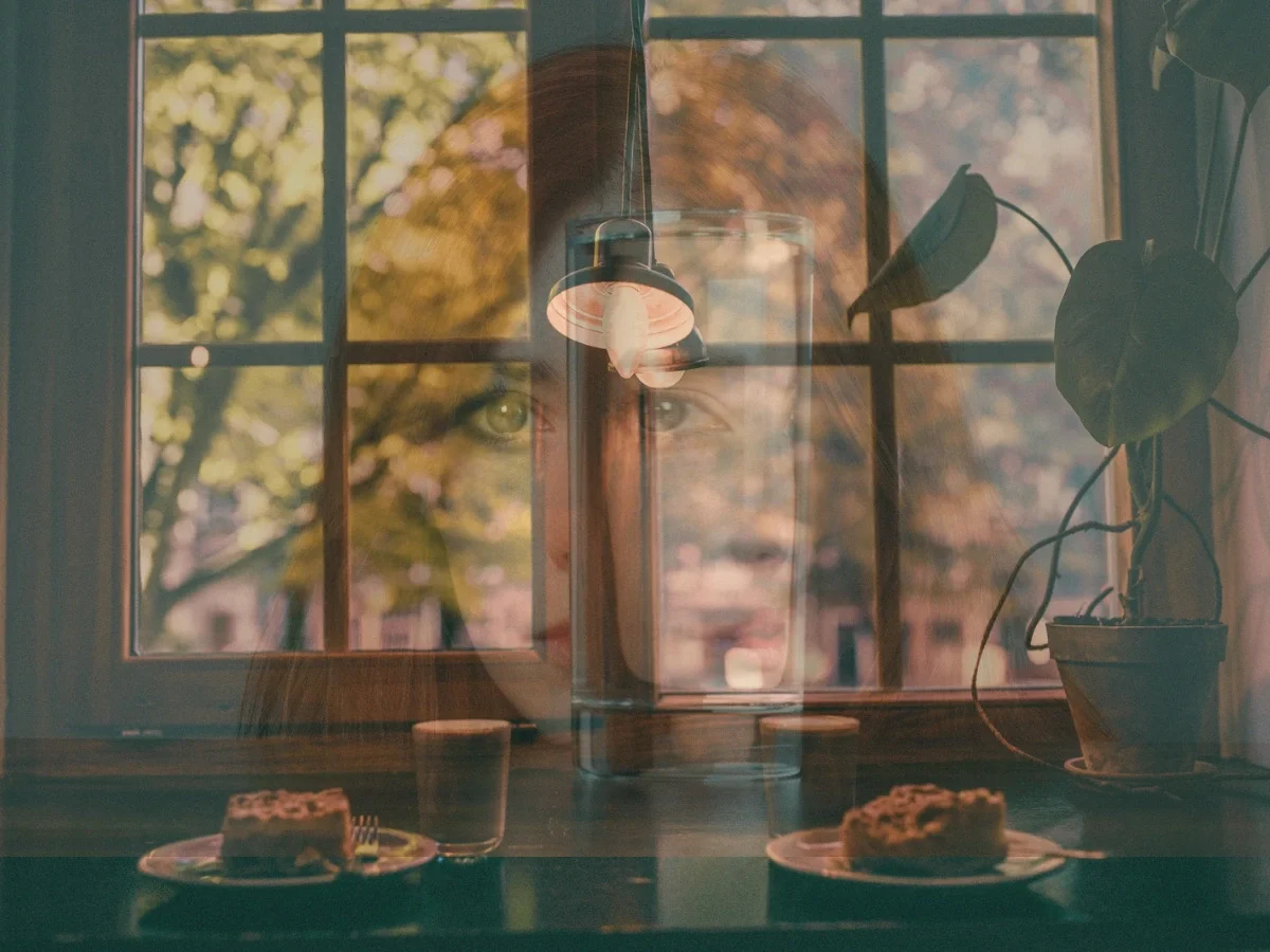 Double-exposure portrait of a woman's face layered over a window, symbolizing visibility without being fully known