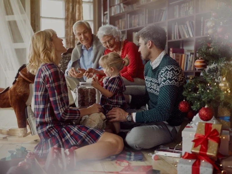 A family gathered around the Christmas tree sharing cozy holiday moments, representing the warmth and togetherness of the Snuggled Season.