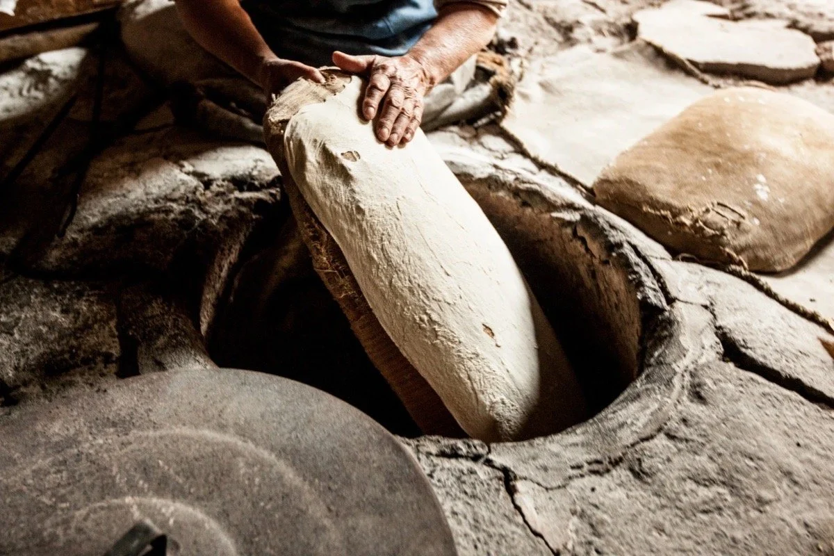 Traditional bread being placed into a stone oven, reflecting culinary memory and storytelling in Turkish and Armenian food traditions in The Bastard of Istanbul.