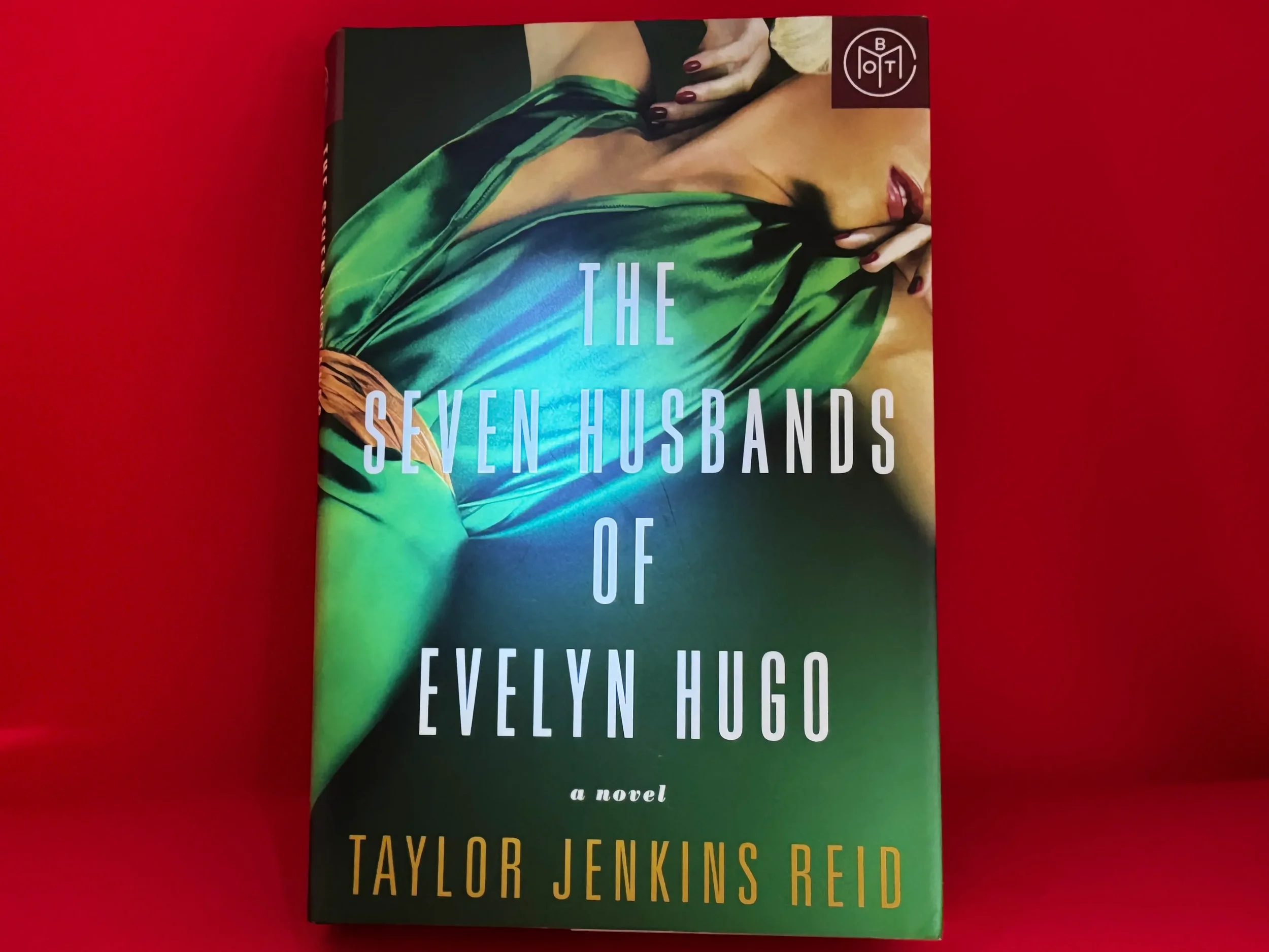 The Seven Husbands of Evelyn Hugo by Taylor Jenkins Reid — green silk gown cover on red background, literary playlist with Peggy Lee and Eartha Kitt