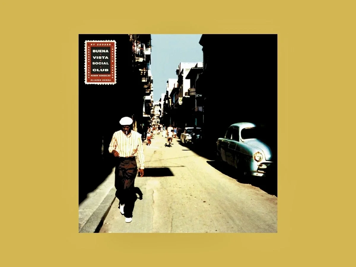 Album cover of Buena Vista Social Club featuring a sunlit Havana street with a vintage blue car and a man walking in shadow.