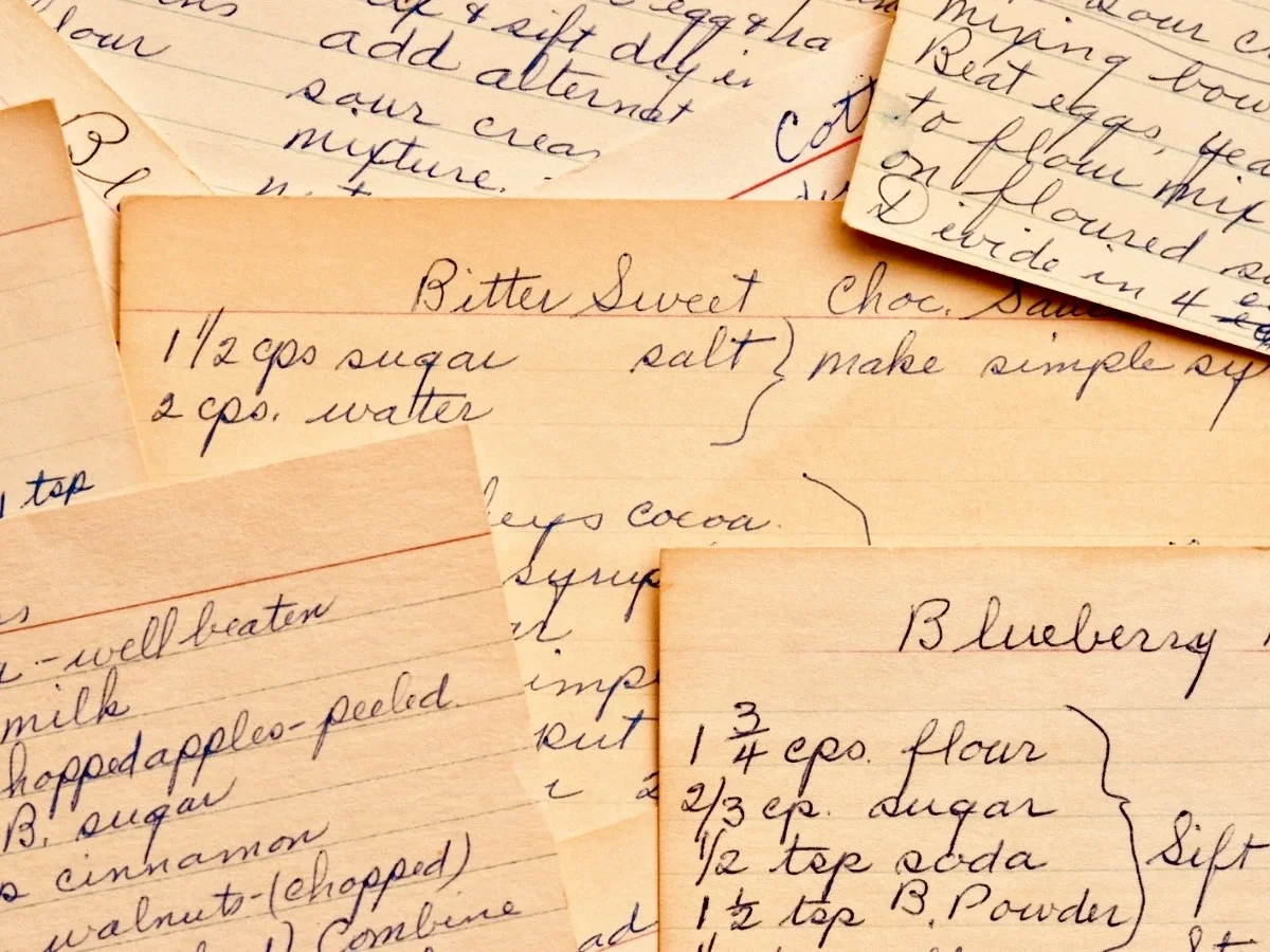 Yellowed, handwritten family recipe cards with cursive instructions like 'season to taste' and 'add enough flour