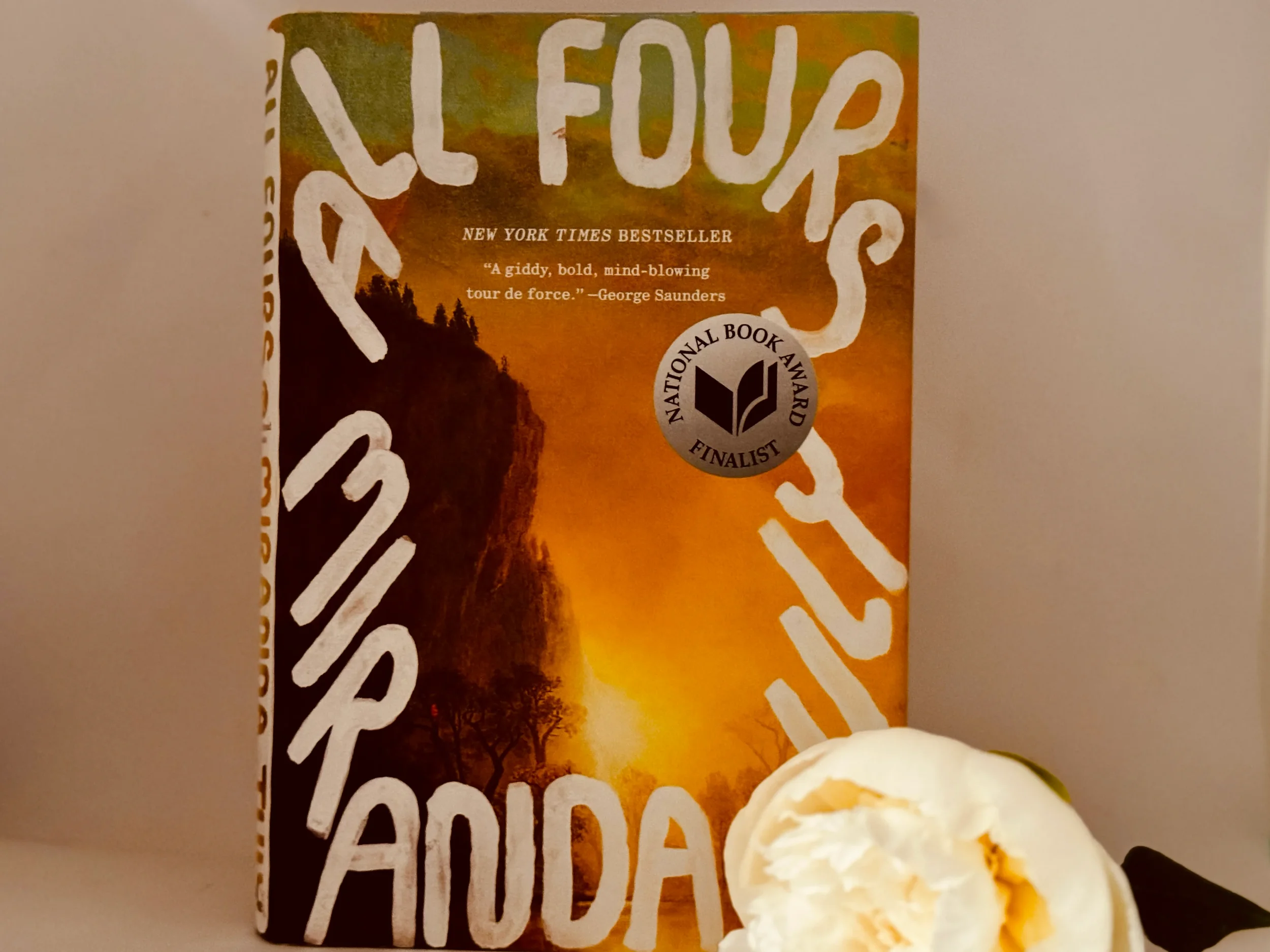 All Fours by Miranda July book cover, a New York Times bestseller and National Book Award finalist, beside a white peony flower