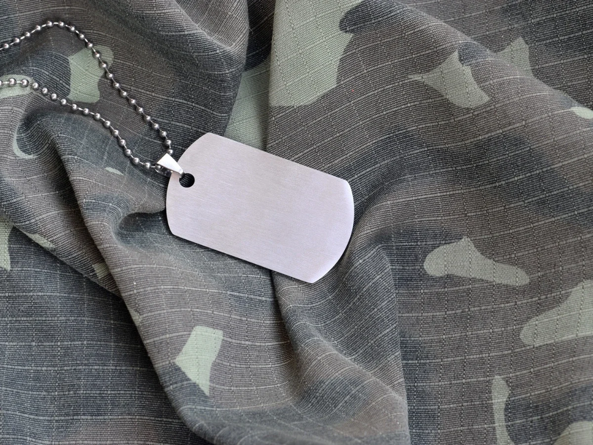 Blank military dog tag on camouflage fabric, symbolizing the unrecorded service of women in Vietnam, inspired by Kristin Hannah's The Women