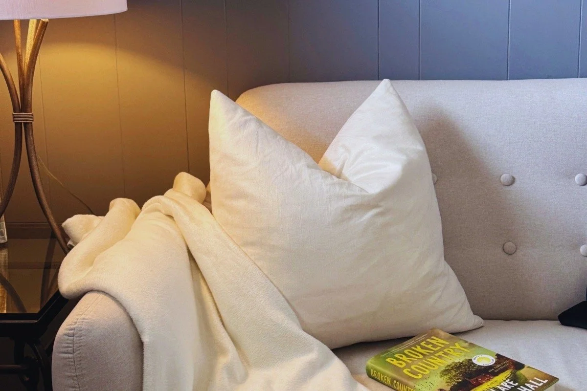 Broken Country by Clare Leslie Hall resting on a sofa in a quiet reading space, reflecting the novel’s thoughtful literary fiction tone and emotional depth.