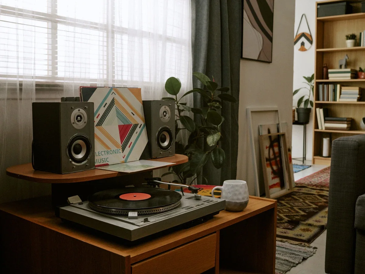 A record player spinning in a plant-filled, art-curated living room, representing the adult ritual of returning to old music with new perspective