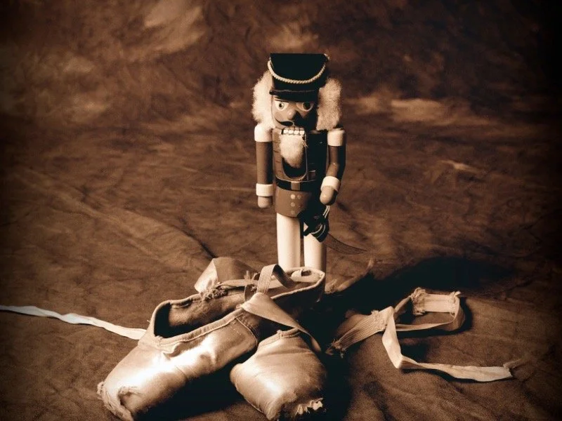 Nutcracker doll beside ballet shoes, a symbol of the holiday ballet.