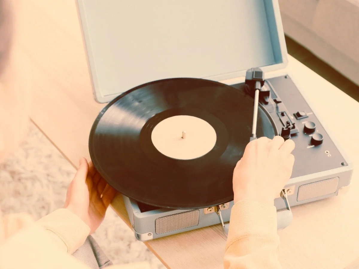 Close-up of hands placing a vinyl record onto a portable record player