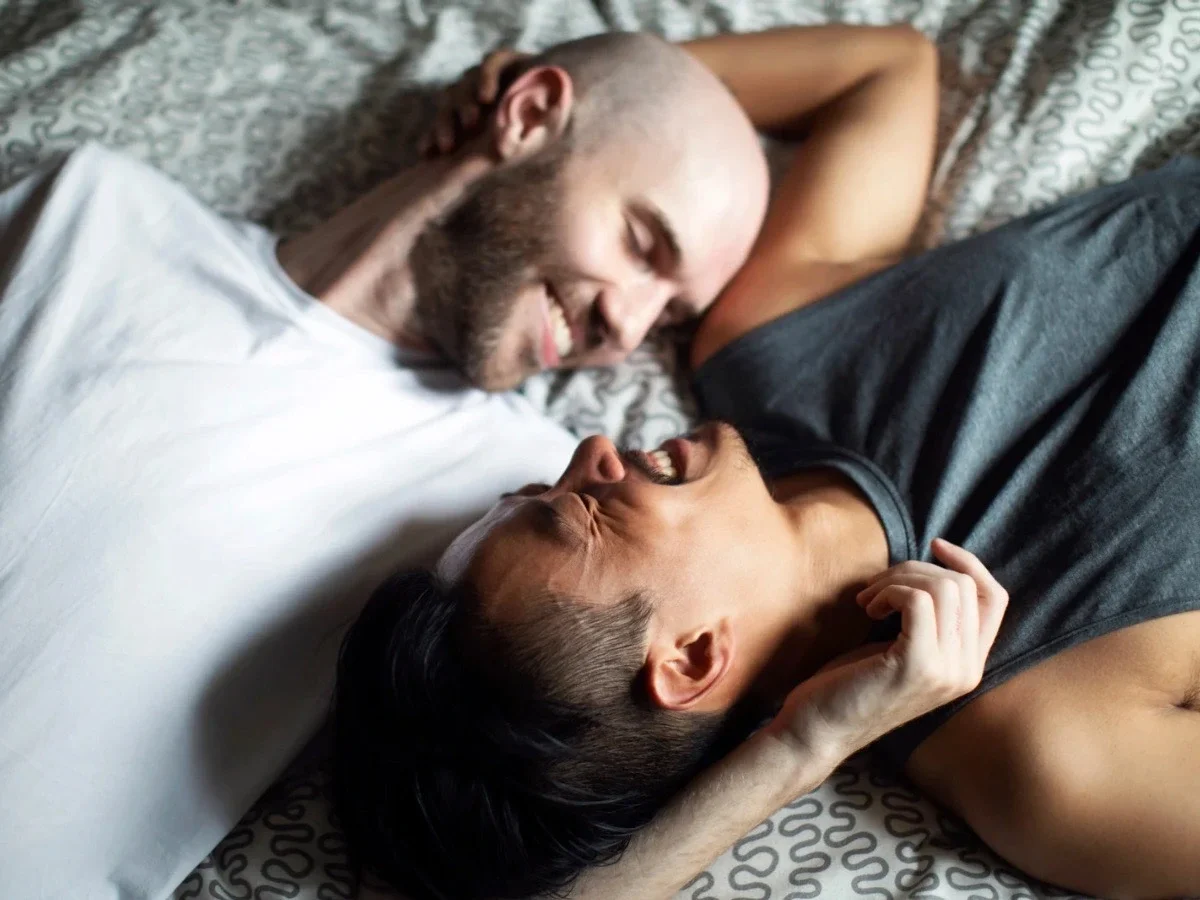 Two men lying together and laughing intimately, reflecting emotional vulnerability and tenderness explored in queer cinema.