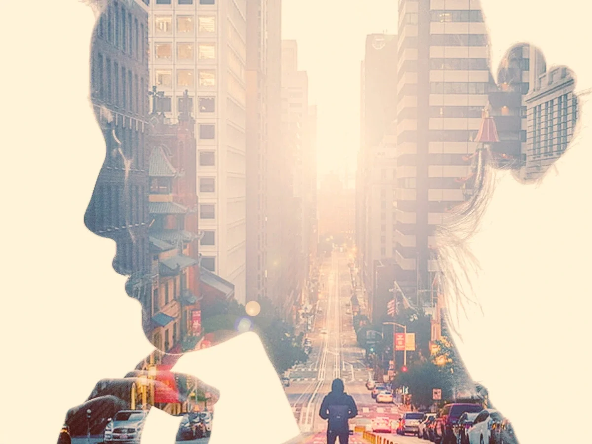 Double exposure portrait blending a woman's silhouette with a city street, symbolizing memory merging with place