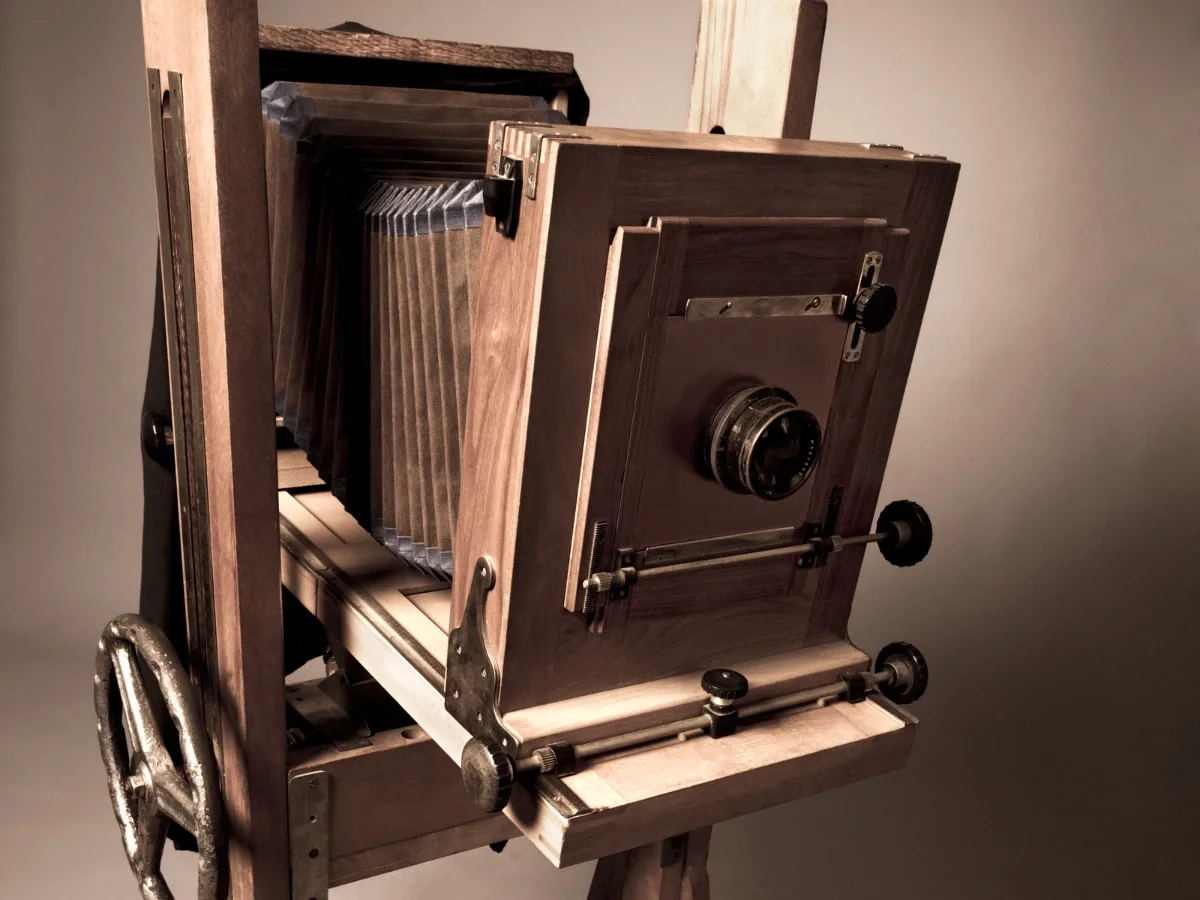 Close-up of an antique wooden large-format view camera with bellows and brass fittings, studio lighting