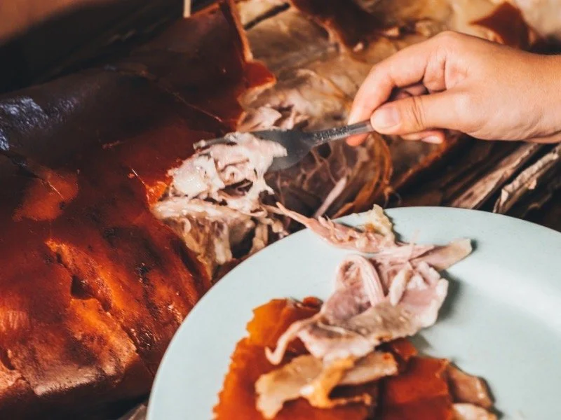 Hand serving tender lechón asado, traditional Cuban roasted pork for Christmas.