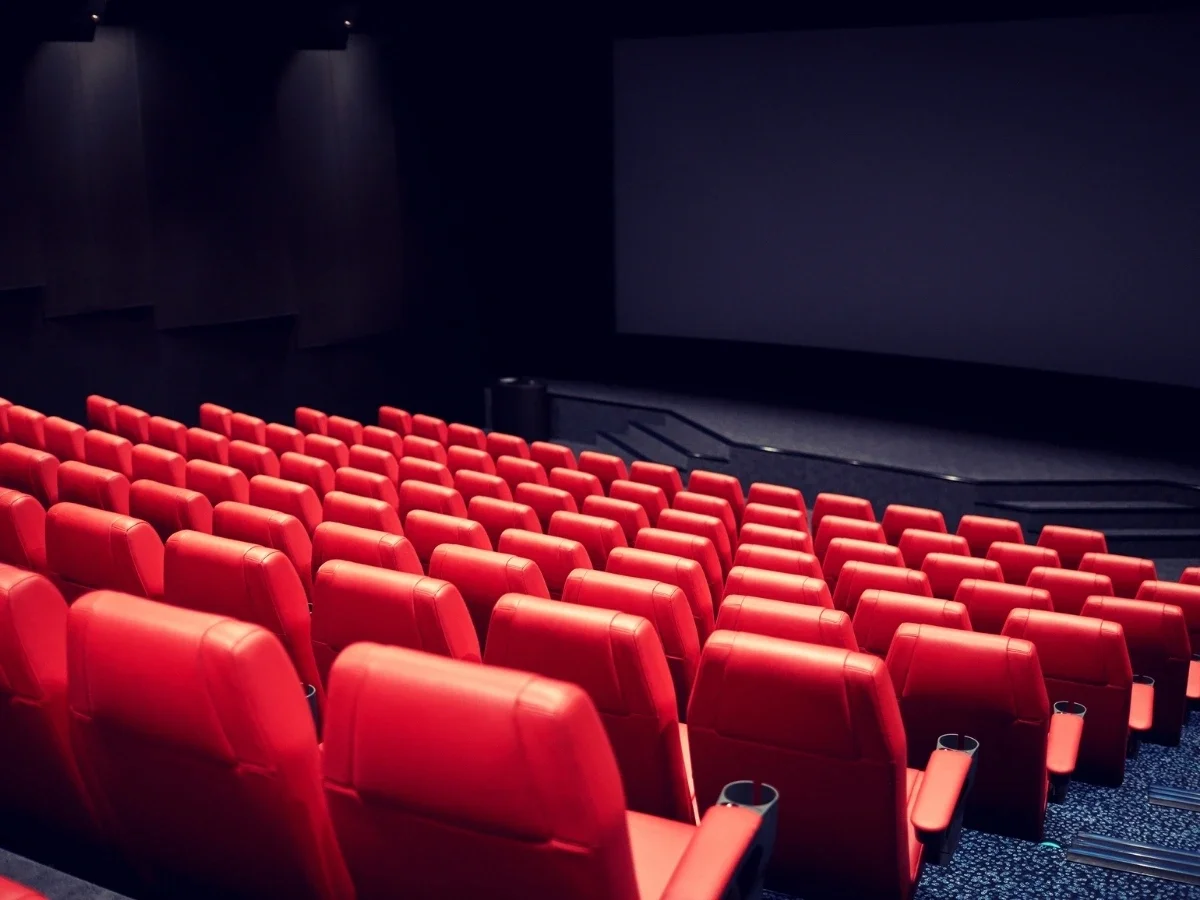 Empty red cinema seats facing a blank screen in a dark movie theater, symbolizing a story waiting to meet its audience
