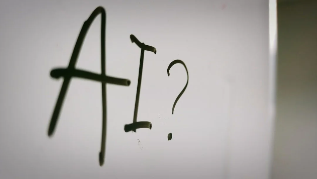 Handwritten 'AI?' in black marker on a whiteboard, close-up with shallow depth of field.