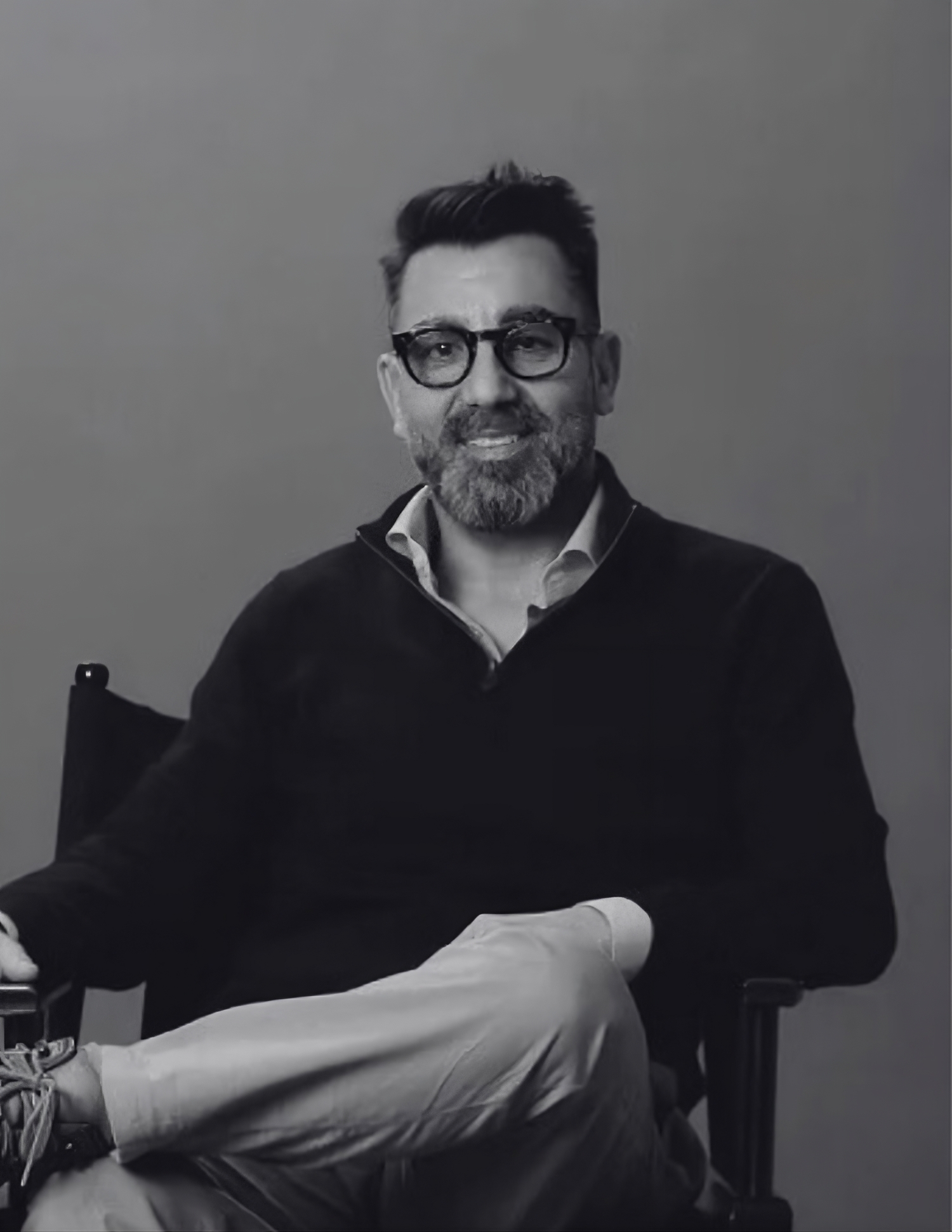 Man wearing glasses, suit, and tie, smiling in black and white photo