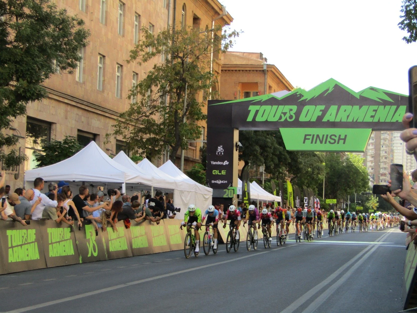 Cyclists race toward the Tour of Armenia finish line as spectators cheer.