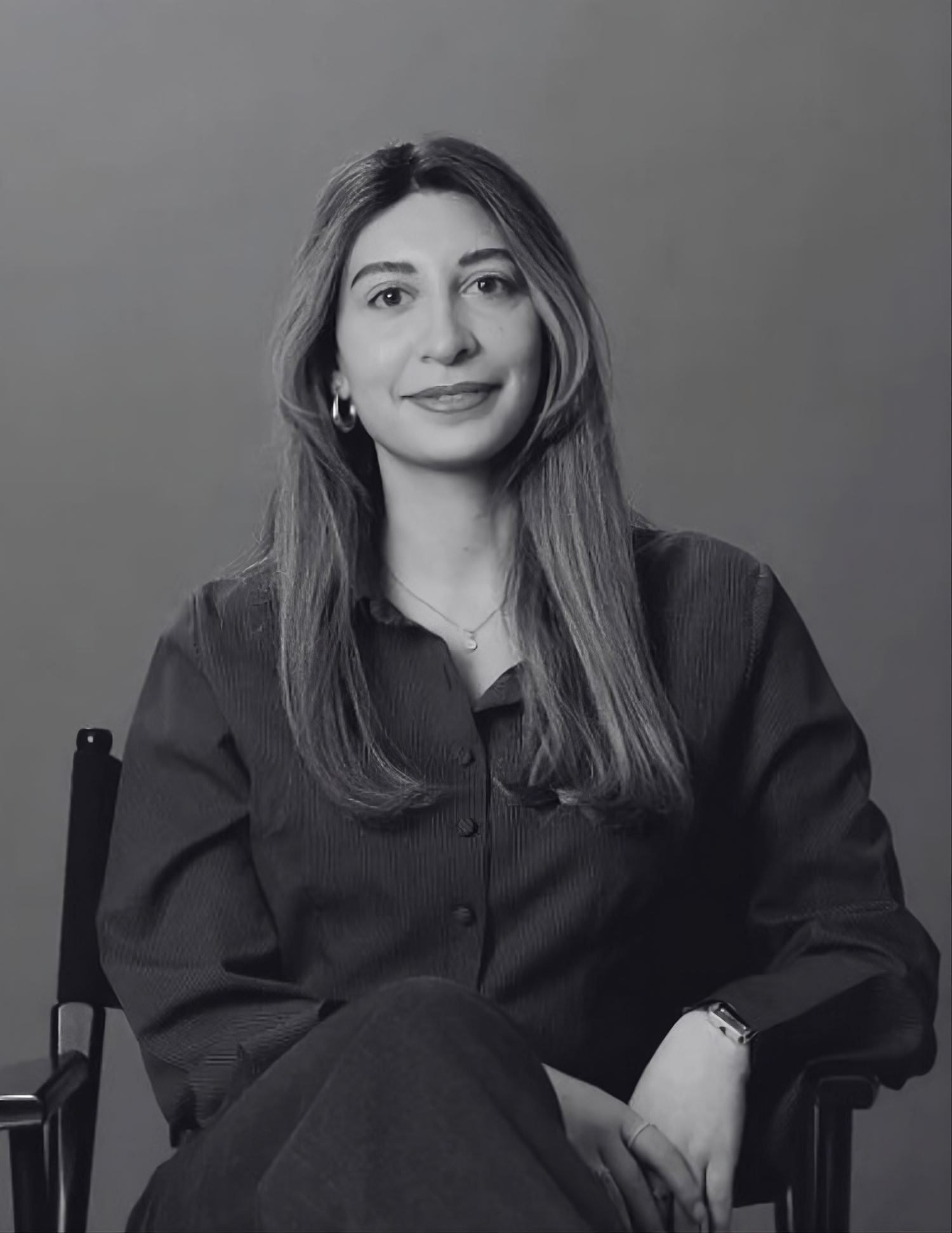 Black and white portrait of a smiling woman with long hair wearing a light-colored shirt and dark top.