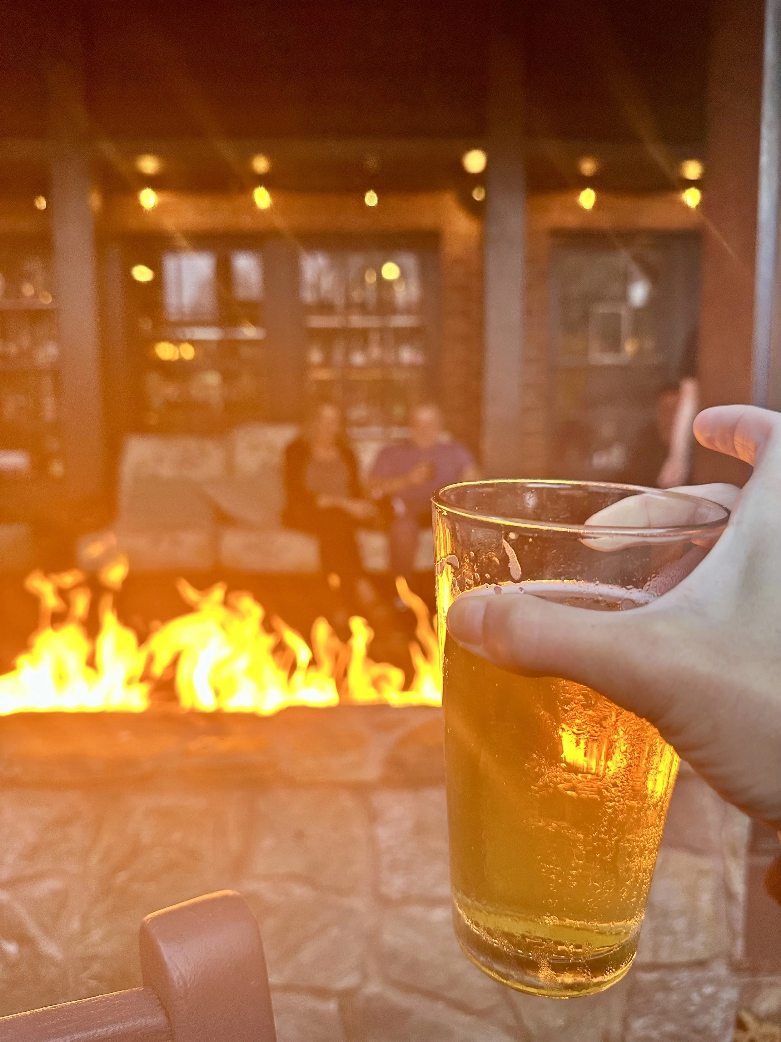 Holding a drink in front of a fireplace