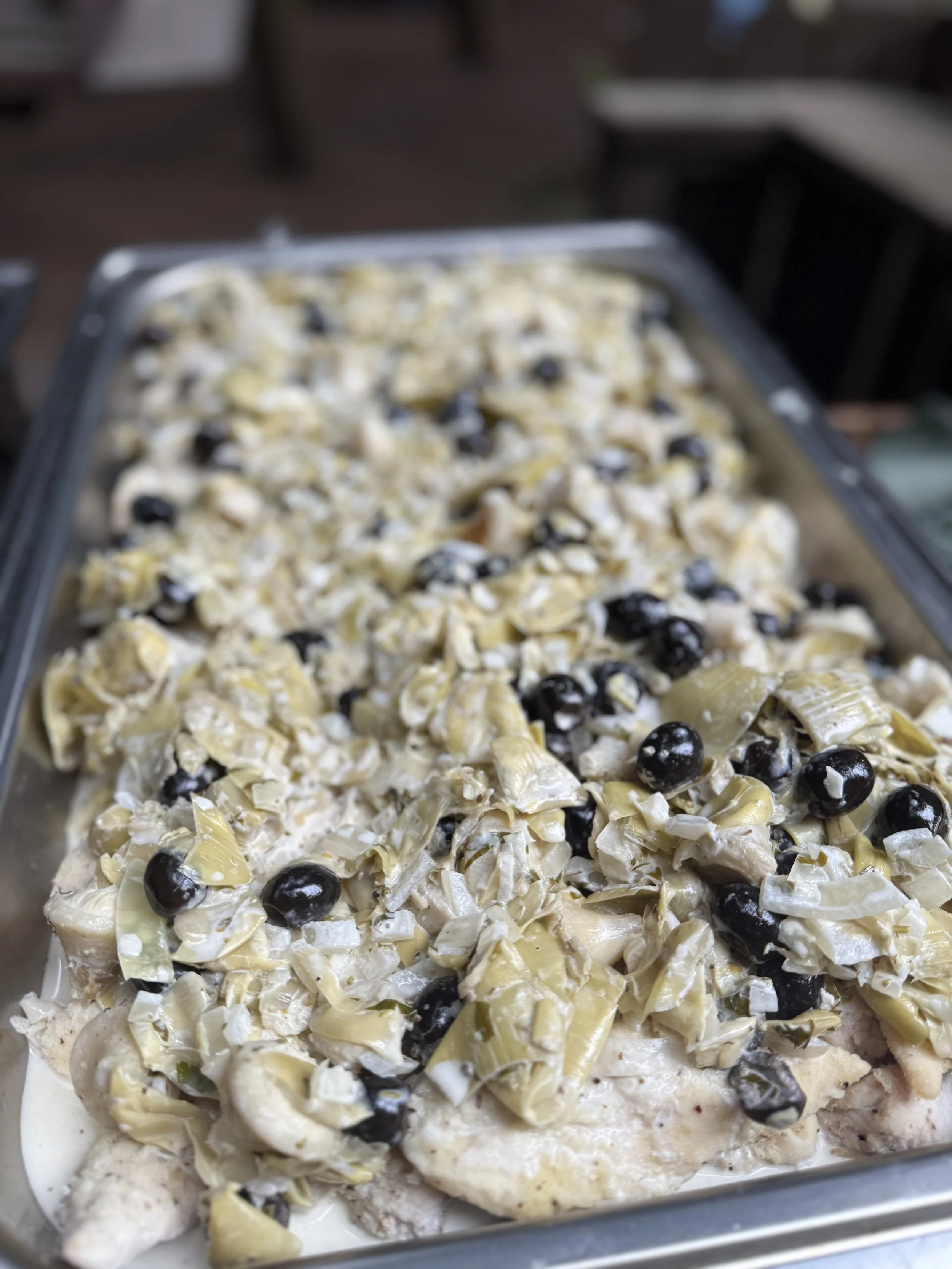 Salad with leafy vegetables, black olives, and chopped artichoke hearts on a tray.