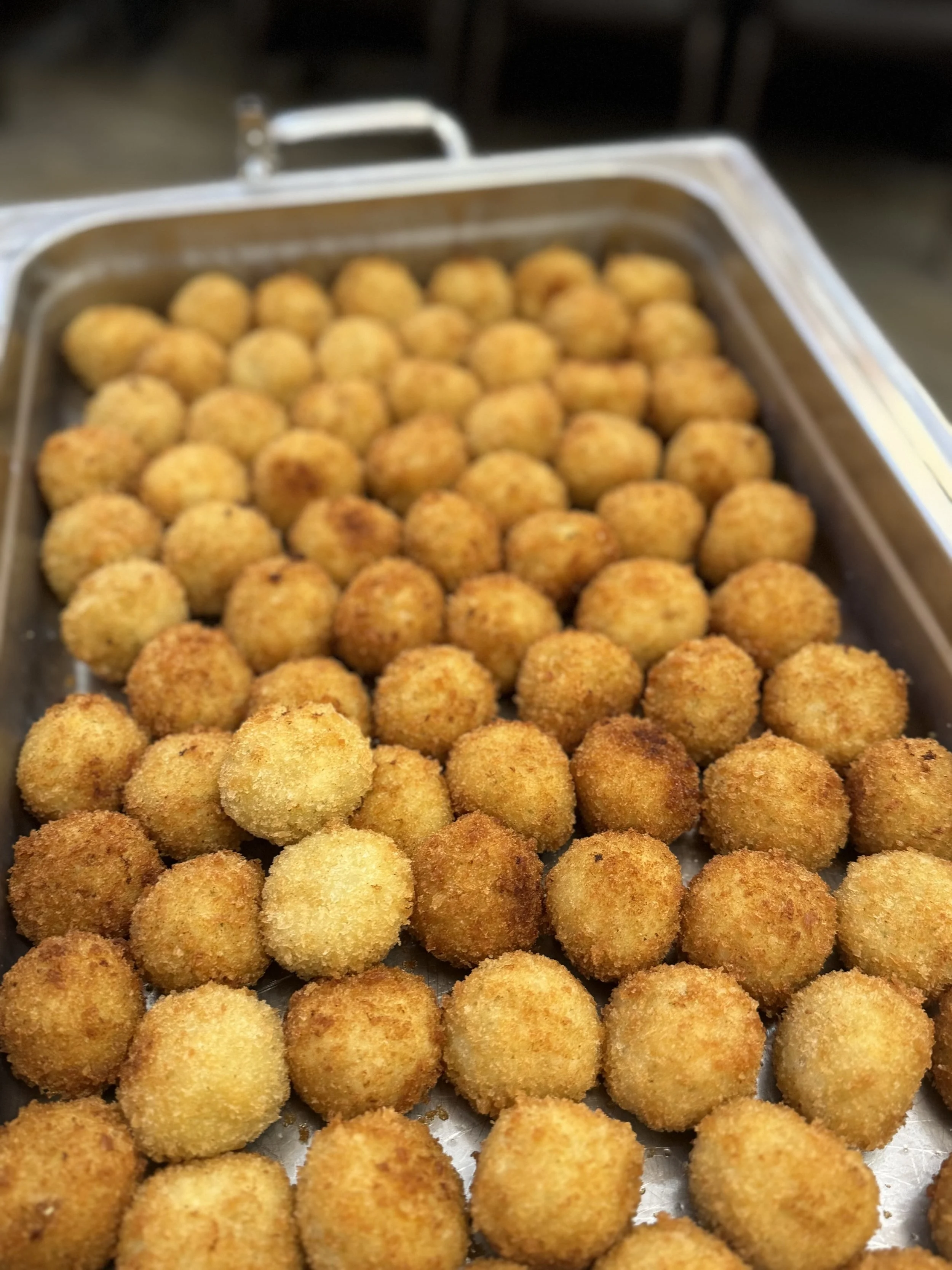 Tray of golden-brown fried arancini balls