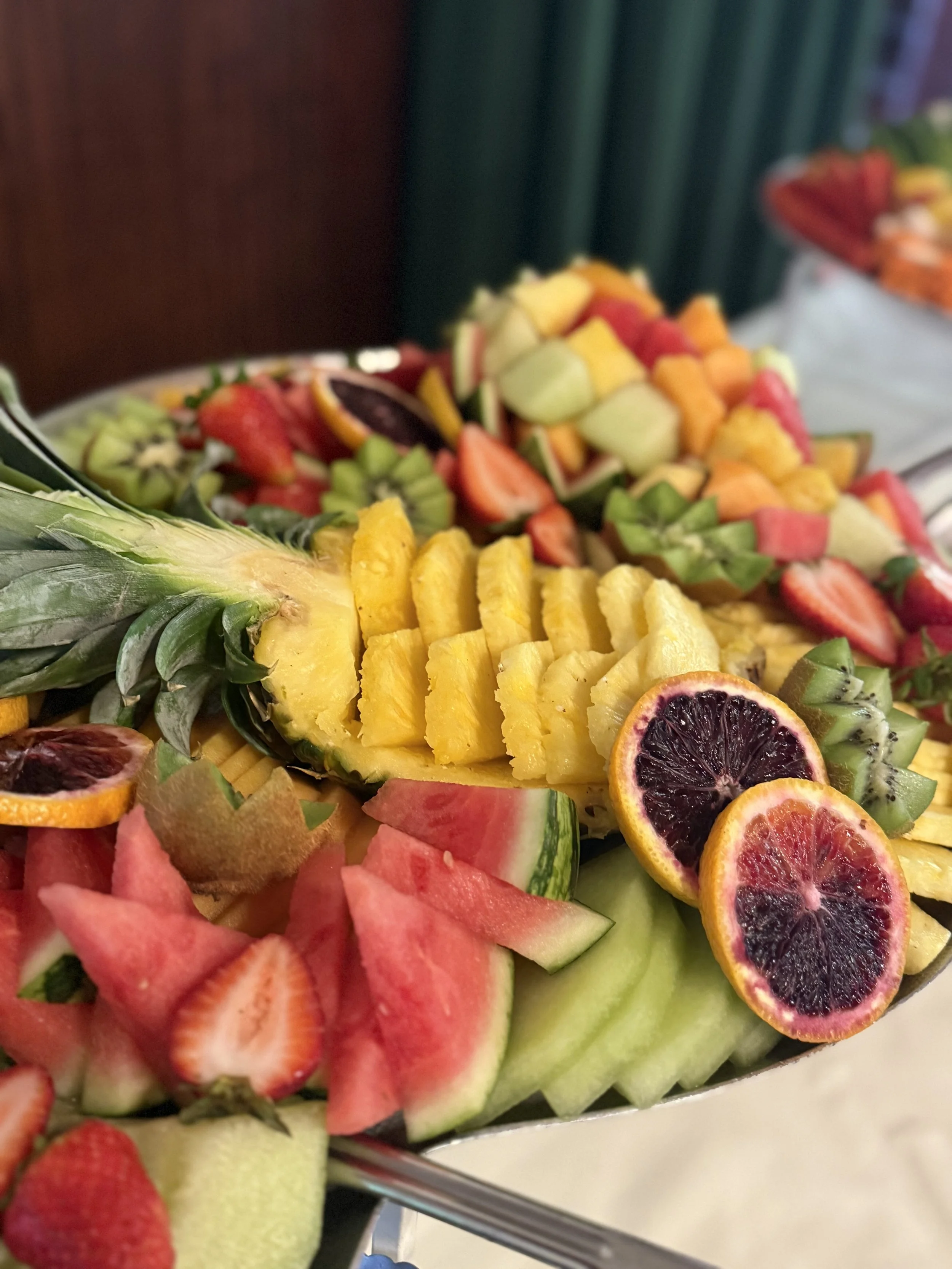 A platter of assorted fresh fruits including pineapple, watermelon, strawberries, kiwi, oranges, and blood oranges.