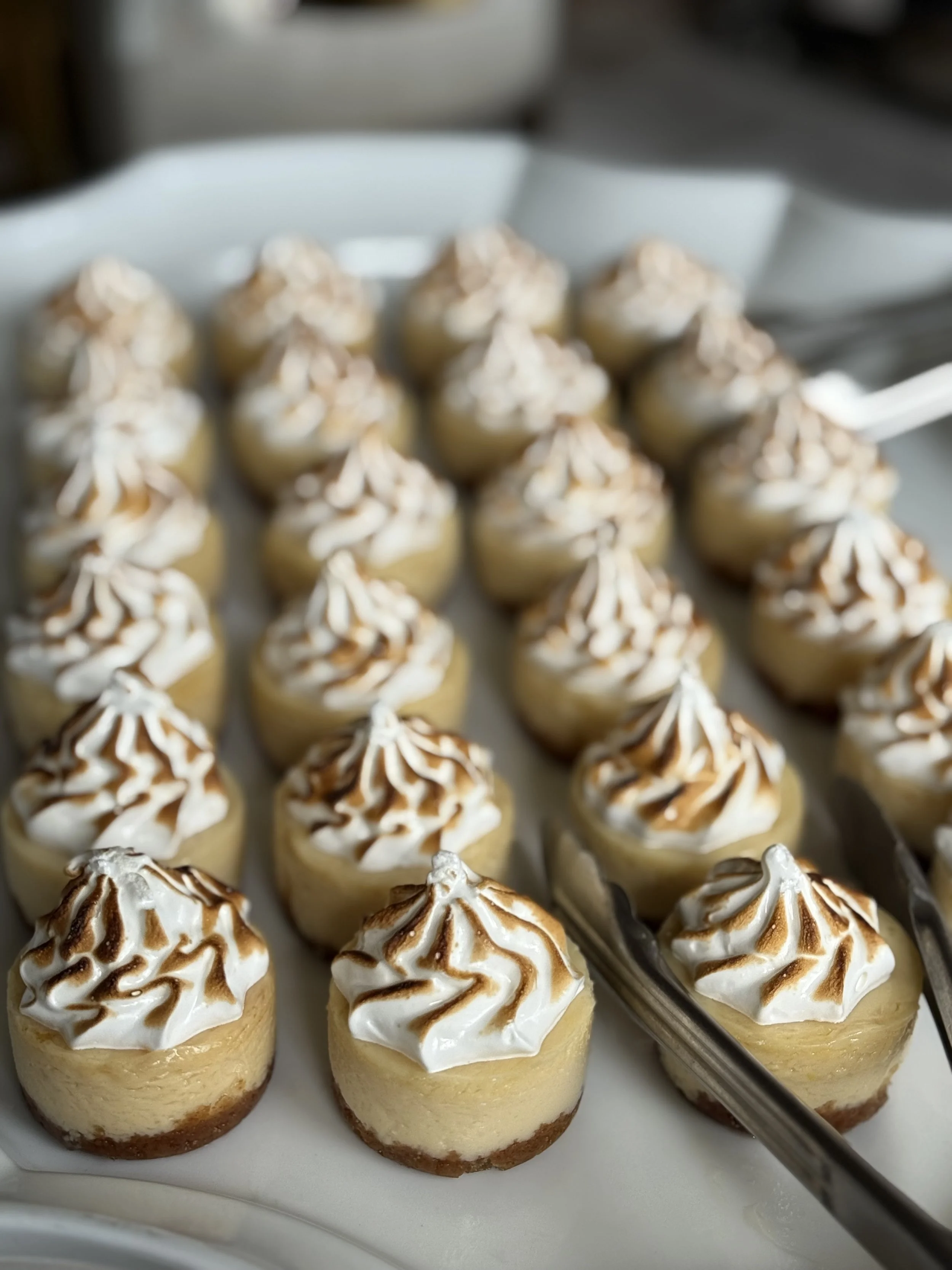 Tray of individual cheesecakes topped with whipped cream and caramel drizzle.