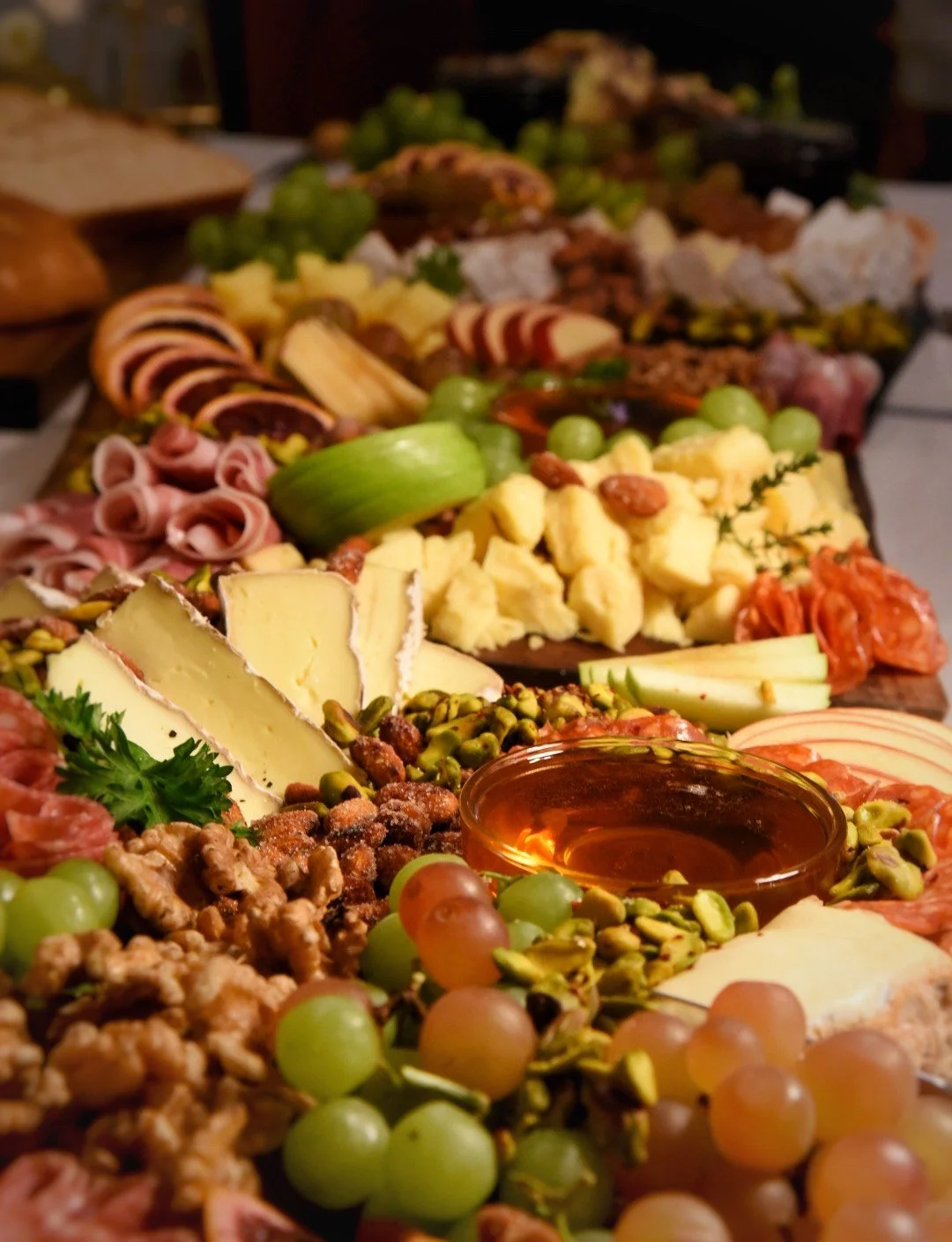 Assorted cheese, grapes, nuts, meats, and crackers on a charcuterie board.