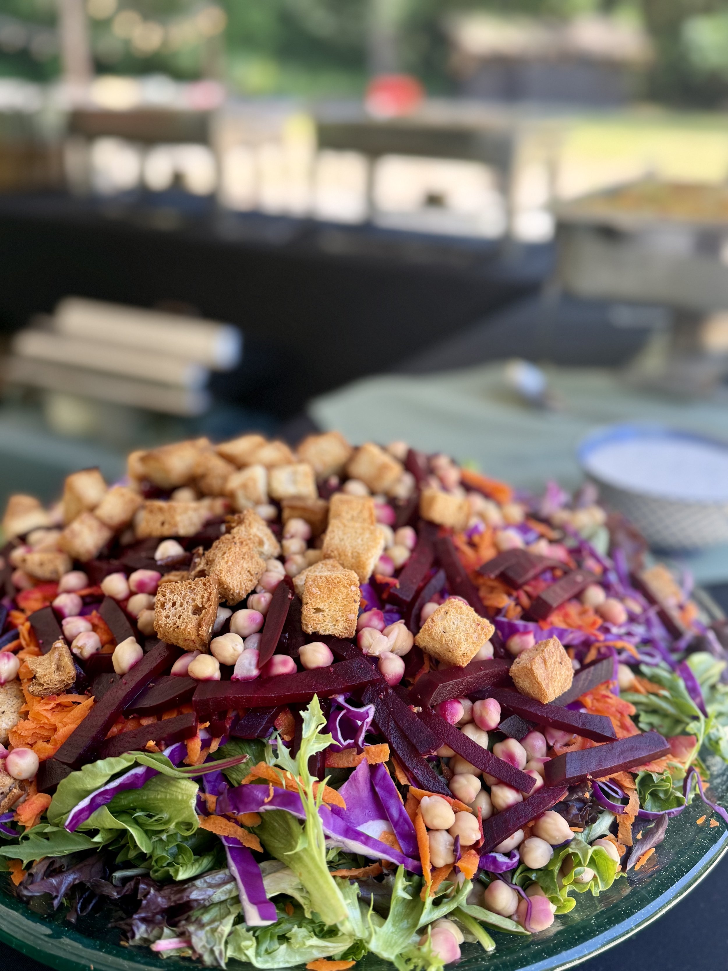 Colorful salad with shredded carrots, purple cabbage, lettuce, chickpeas, croutons, and beet strips.