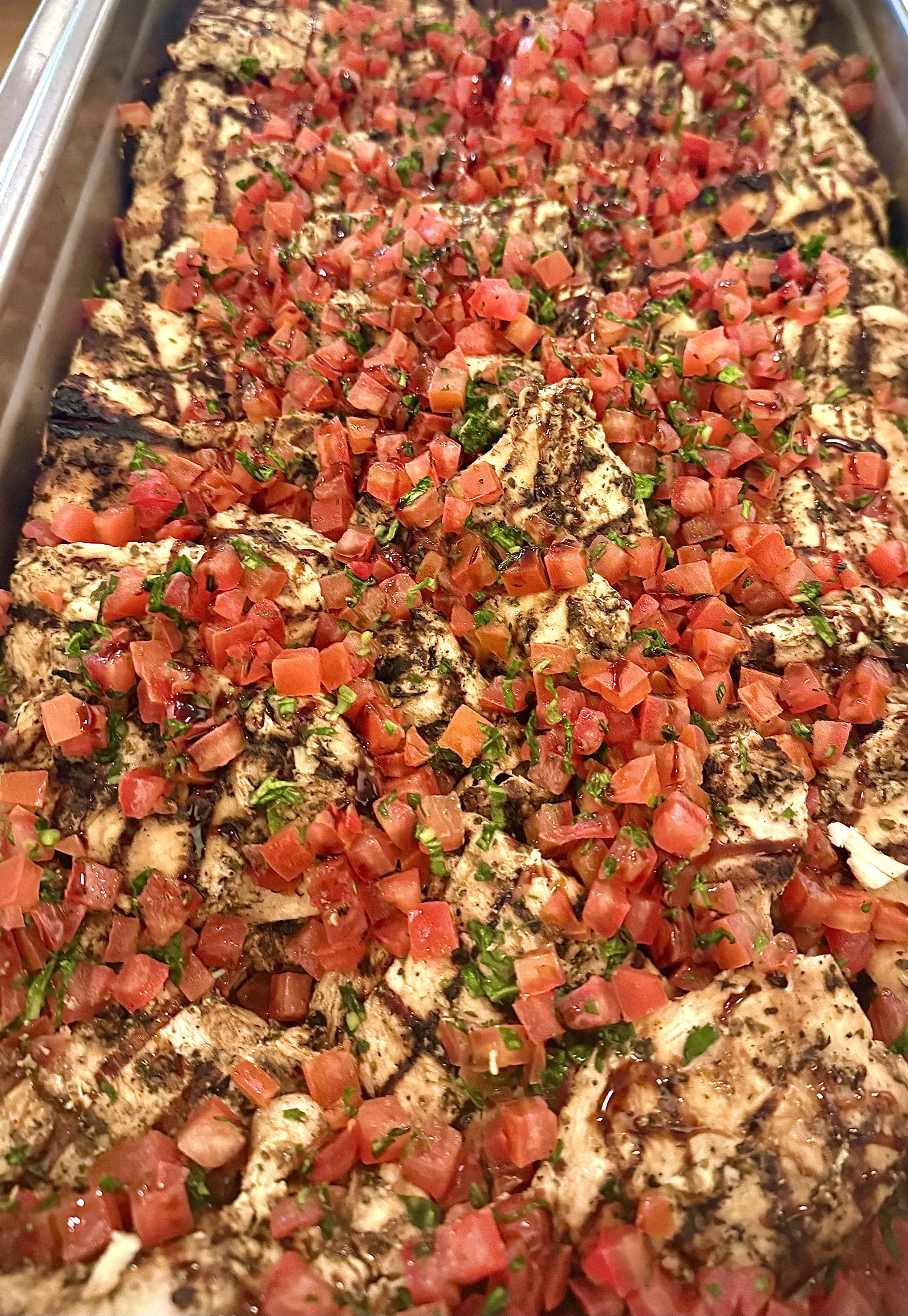 Grilled chicken breast topped with chopped tomatoes, chopped green herbs, and drizzled with balsamic glaze.
