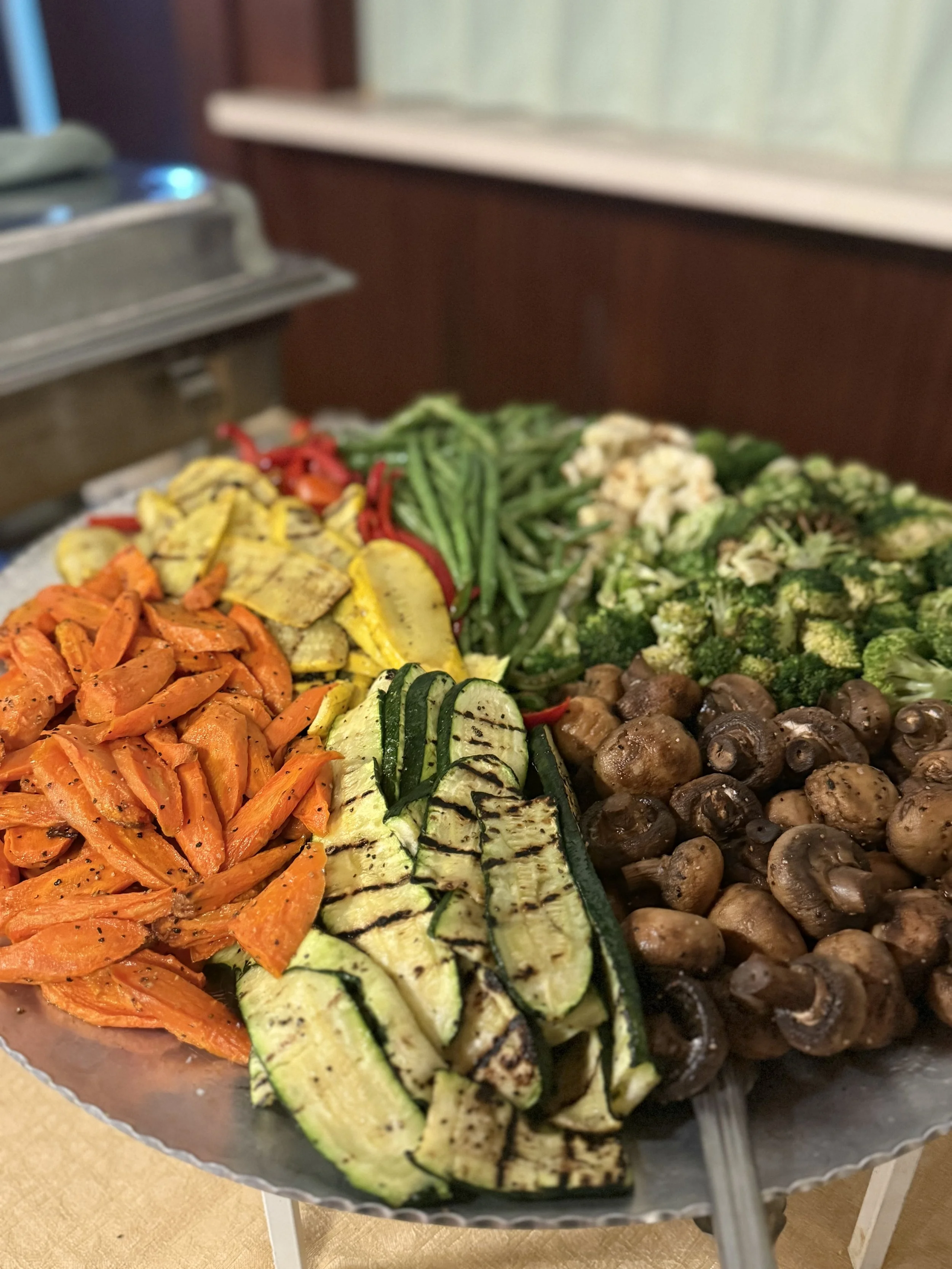 A platter of grilled vegetables including carrots, zucchini, broccoli, mushrooms, eggplant, and peppers.