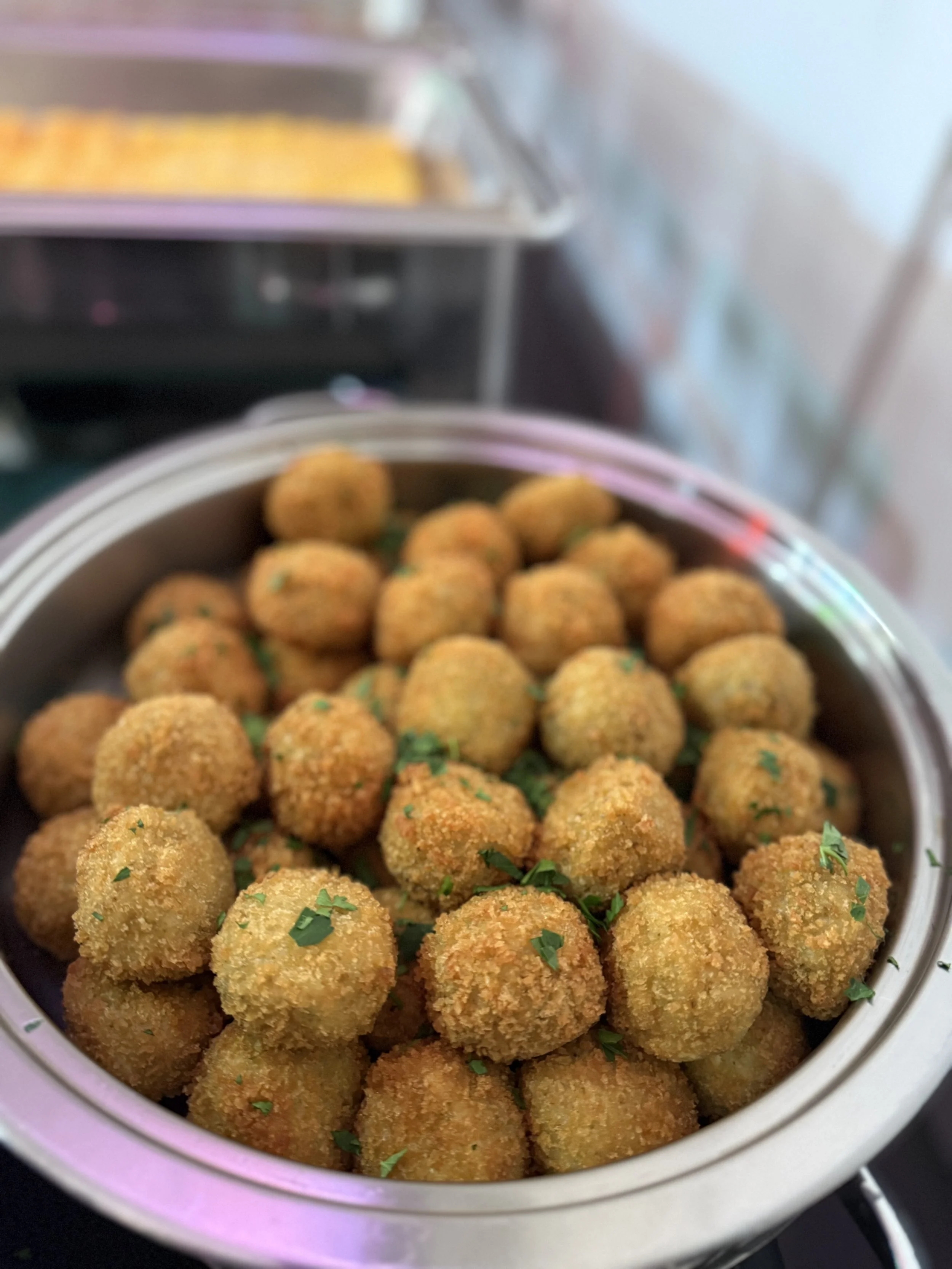 A pot filled with breaded, fried croquettes garnished with chopped parsley.
