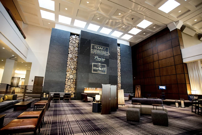 Lobby of a hotel with a large dark stone fireplace, wood log decor, and modern seating.