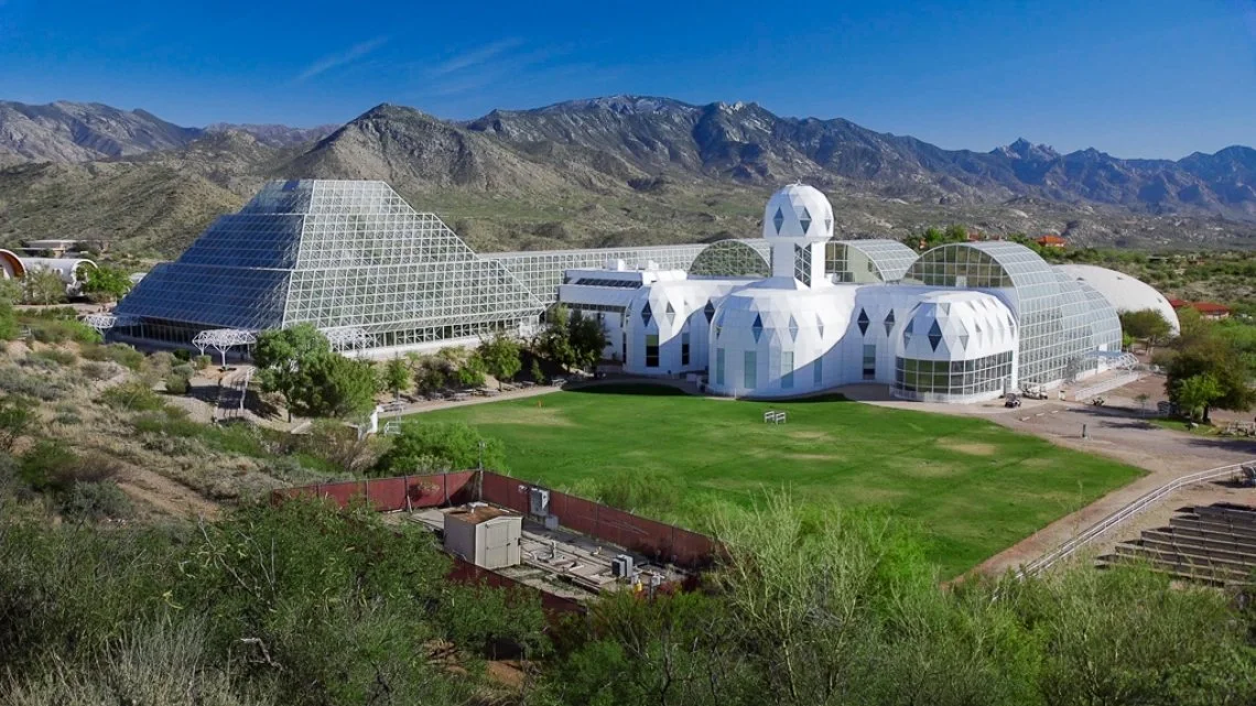 Unique modern building with glass domes and pyramids in a desert landscape with mountains in the background